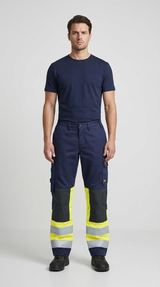 Mand i mørkeblå t-shirt og arbejdsbukser med neongule detaljer og refleksstriber.