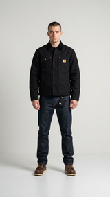 Mand iført en sort Carhartt-jakke, mørkeblå jeans og brune støvler mod en ensfarvet hvid baggrund.
