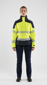 Kvinde i gul og mørkeblå high-visibility arbejdsjakke med refleksstriber og mørkeblå bukser på hvid baggrund.
