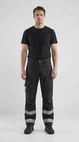 Mand i sort t-shirt og sorte arbejdsbukser med refleksstriber mod en lys baggrund.