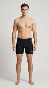 Mand i sorte ribbede boxershorts stående foran en lys baggrund.