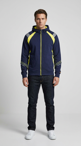Mand i mørkeblå hættetrøje med gule detaljer og mørke jeans mod en lys grå baggrund.