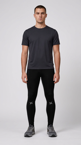 Mand i mørkegrå t-shirt, sorte træningstights og grå sneakers mod en lys baggrund.