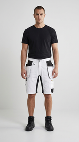 Mand i sort t-shirt, hvide arbejdsshorts med sorte lommer og sorte støvler på en lys baggrund.