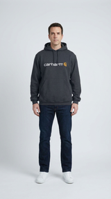 En mand i en mørkegrå Carhartt-hættetrøje, blå jeans og hvide sneakers mod en hvid baggrund.