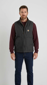 Mand i bordeauxrød trøje og sort Carhartt-vest med blå jeans mod en hvid baggrund.