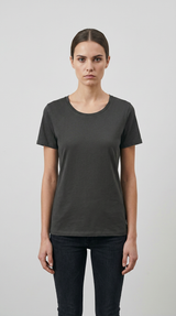 Kvinde iført en mørkegrå kortærmet t-shirt og sorte jeans mod en lys baggrund.