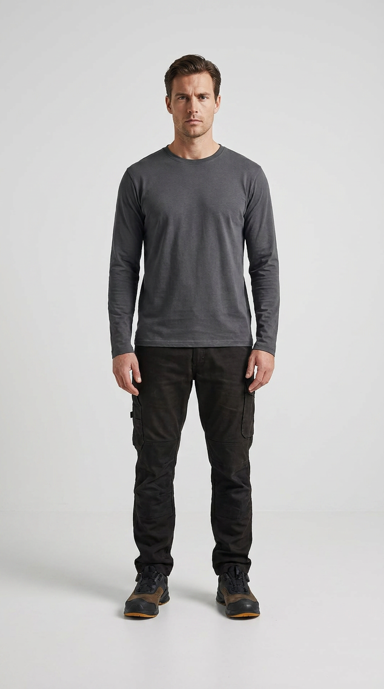 Mand iført grå langærmet t-shirt, mørke cargobukser og støvler foran en hvid baggrund.