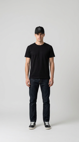 Mand i sort t-shirt, mørkeblå jeans og en sort kasket mod en enkel grå baggrund.