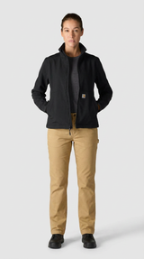 Kvinde iført en sort Carhartt-jakke og beige arbejdsbukser mod en lys baggrund.