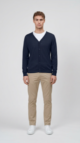 Mand i mørkeblå cardigan, hvid t-shirt, beige bukser og hvide sneakers mod en lys baggrund.