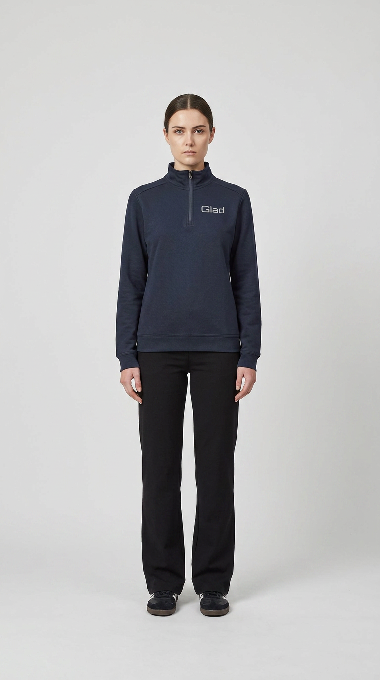 Kvinde i mørkeblå sweatshirt med Glad-logo og sorte bukser på en hvid baggrund.