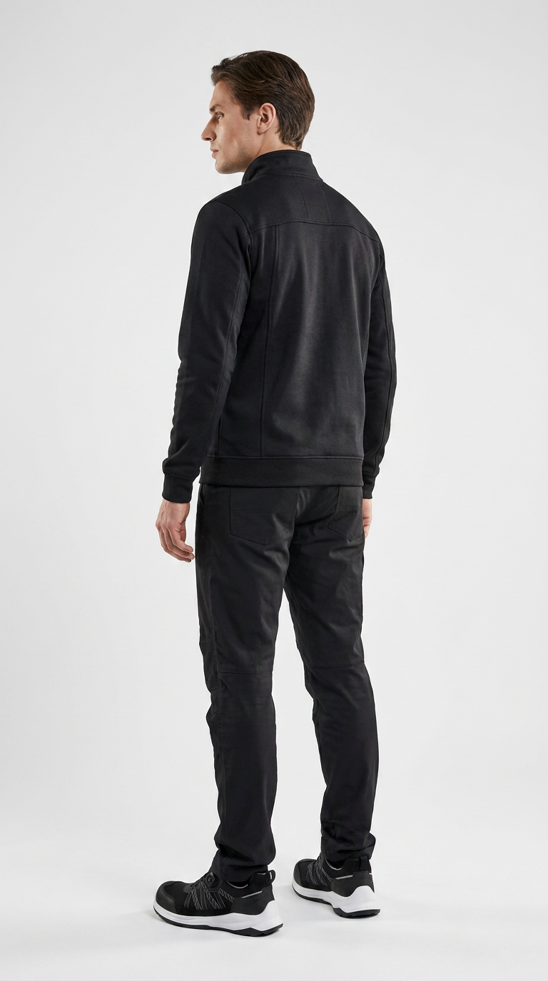 Mand set bagfra iført en sort sweatshirt med lynlås, sorte bukser og sneakers mod en hvid baggrund.