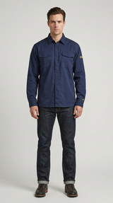 En mand i en mørkeblå langærmet arbejdsskjorte, mørke jeans og brune støvler foran en grå baggrund.