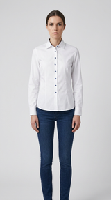 Kvinde i hvid langærmet skjorte med blå knapper og blå jeans mod en lys baggrund.