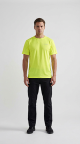 Mand i neon-gul t-shirt og sorte bukser stående foran en hvid baggrund.