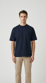 Mand i en mørkeblå t-shirt med brystlomme og beige bukser mod en hvid baggrund.