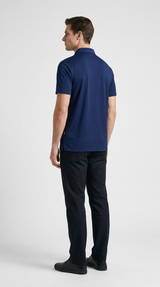 Mand set bagfra iført en mørkeblå polo shirt og sorte bukser mod en hvid baggrund.
