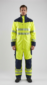 Mand i gul og mørkeblå high-visibility kedeldragt med refleksstriber på en grå baggrund.