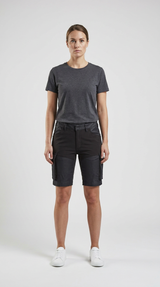 Kvinde i grå t-shirt og sorte cargoshorts stående mod en hvid baggrund.