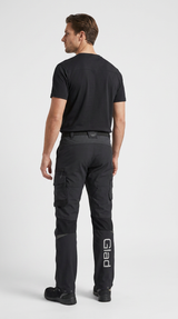 Mand set bagfra i sort arbejdstøj med t-shirt og bukser med hvidt Glad-logo på benet.