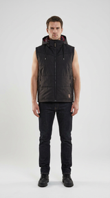 Mand iført en sort vest med hætte, mørke jeans og sorte støvler mod en hvid baggrund.